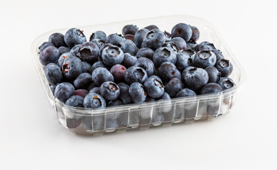 Fresh and raw blueberries in plastic tub. Isolated and on white background.