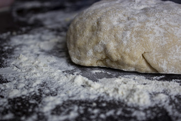Fototapeta na wymiar Unbaked dough on the table with the flour around