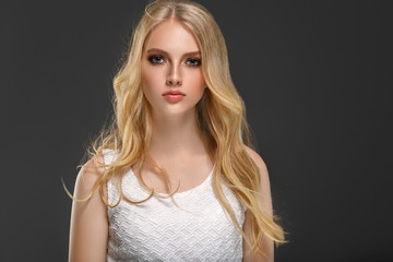 Beautiful woman with long blonde hair over gray background beauty female