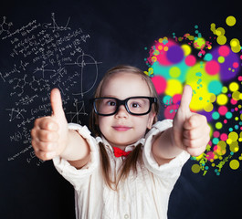 Little genius girl on chalk board in classroom with symbol of right and left hemispheres of the brain - science and arts elements