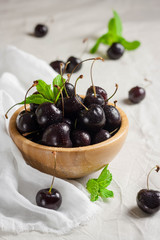 Black sweet cherry and mint on the wooden table, selective focus
