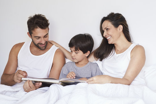 Family book at bedtime in bed, smiling