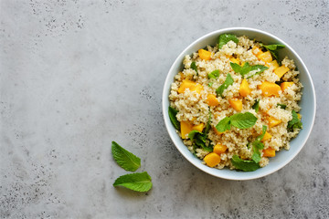 Quinoa salad with baked pumpkin and mint in bowl. Lemon honey dressing for salad. Healthy food concept

