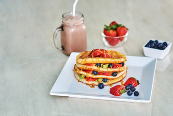 Delicious sweet American pancakes on a plate with fresh fruits and syrup