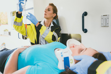 Medic taking care of injured woman with whiplash collar in ambulance