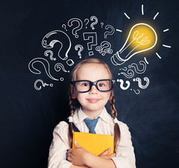 Child ideas. Smiling child school student with yellow book, lightbulb and chalk question marks....
