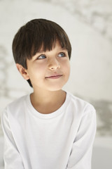 Thoughtful boy in white looking up