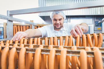 Butcher man making sausages ready to be smoked putting them on rack