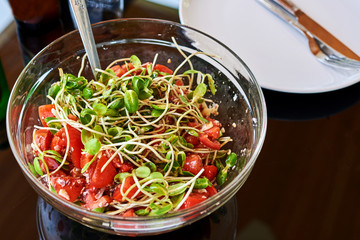 Dish of Salad with green young sunflower sprouts,  cherry tomatoes  and pumpkin seed. Vegetarian food concept.