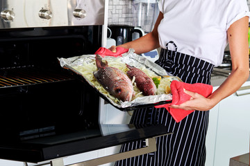  Housewife prepares  fish in the oven. Cooking in the oven.