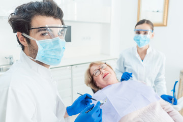 Dentist man in his surgery looking into camera