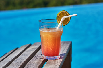 Cocktail at the edge of the swimming pool. Orange cocktail . on the background of the swimming pool