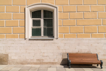 Empty bench against the wall with a window.