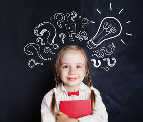 Child ideas. Happy child school student with lightbulb and question marks in classroom on blackboard