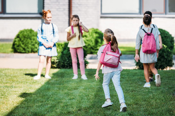rear view of pupils with bakpacks waling by school garden