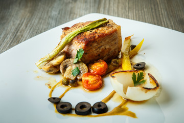 roasted meat decorated with grilled tomato, mushrooms, yellow pepper, green onion and black olive