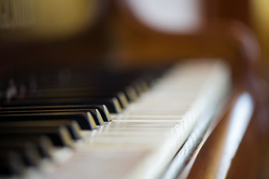 Macro shot of the keyboard of an old out of tune rustic piano. Ivory keys are worn out and broken