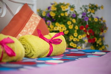 A king sized bed prepared for a newly wed couple with fresh yellow towels and fresh bed linens. Pink ribbon decorations.  

