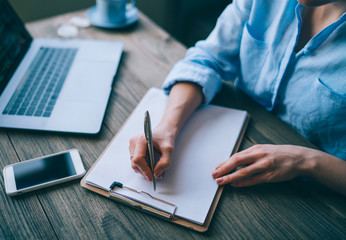 Woman working in the office. Work process in modern office. Young account manager working at wooden table with new business project. Typing contemporary laptop keyboard. Film effect. Selective focus.