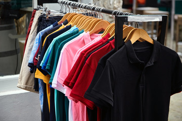 Obraz premium Colorful polo t-shirt for the man on wooden hangers in a retail shop