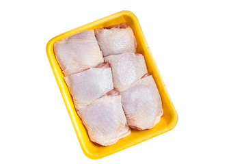 Raw and uncooked chicken thighs in a yellow plastic container. Meat of poultry in tray, isolated on white background