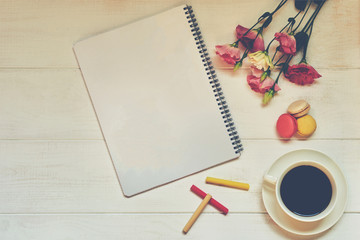 Top view of creative woman's desktop with spiral notepad, flowers, coffee cup and other items on the vintage white table. Home office desk for woman. Creative planning concept. Mock up. Vintage style.
