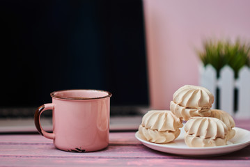 Feminine workplace. Closeup cup hot chocolate, worksplace with laptop and flowers on the background. Cozy work space on old wooden table. Creative planning concept.  Vintage style. Selective focus.