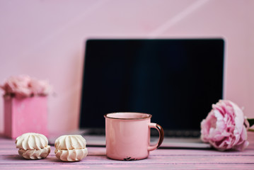 Open laptop  on a vintage wooden table. Portable net-book and cup of hot drink, electronic distance work via internet during coffee break. Feminine workplace. Vintage style. Selective focus.