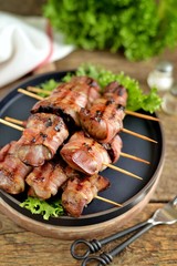 Grilled Shish kebab from a turkey liver in bacon on wooden skewers.