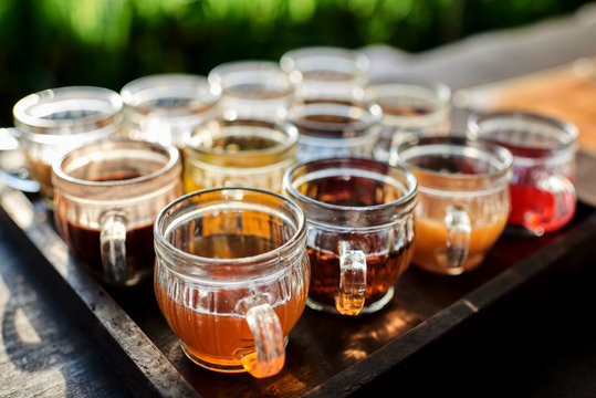 Coffee With Multiple Assorted Types And Flavors  Tea In Identical Mugs For Degustation On Farm In Indonesia, Bali. Fruit And Herb Tea Testing Set. Selective Focus.