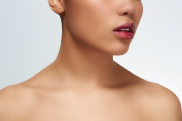 Young woman studio standing isolated in white wall touching neck looking camera cocky close-up...