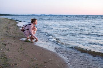 Nice teenager girl is walking near the sea at the seashore at the sea coast in the evening