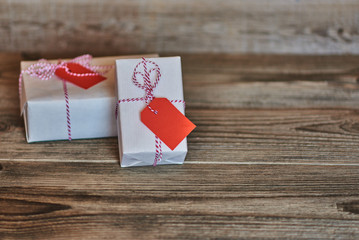 Vintage gift boxes on the shabby wooden background. Gift box wrapped white paper,  tied red & white baker twine with tag. Vintage Style. Background for your design. Holiday packing concept.
