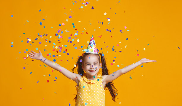 happy birthday child girl with confetti on yellow background
