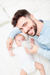 Vater lächelt stolz und gibt Baby die Flasche