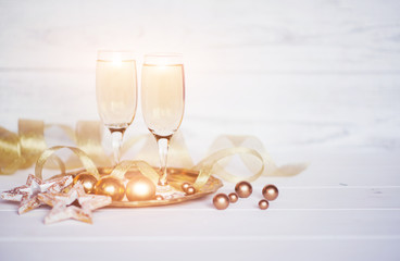 Christmas holiday background. Celebration theme. Two glasses of champagne with gold ribbon and Christmas decor on the blurred white  background. Celebration concept, free space for text.