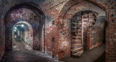 Kaliningrad, Russia - May, 2018. Brick underground corridor and light in end spiral staircase. Panoramic view.
