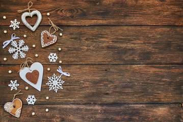 Snowflakes and wooden hearts on the brown wooden table. Christmas background with copy space. Top view.