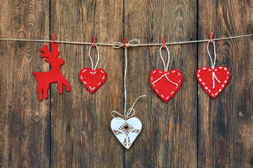 Red hearts hanging on a clothesline with a wooden background.