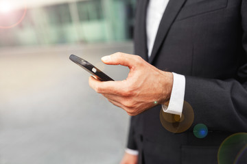 Close up of a man using mobile smart phone. Business and information technology concept. standing street with city in the background
