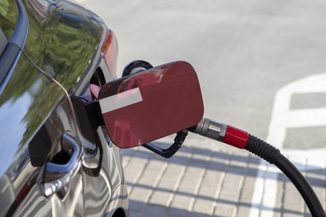 Fueling car with petrol pump at a gas station.