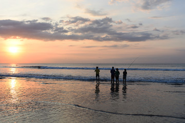 Silhouette of asian children in action when fishing at sunrise in the nature ocean at the early morning when sunrise time.