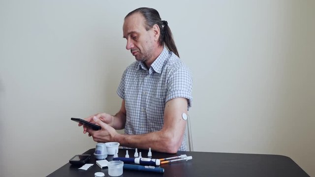 A man brings to the hand the smartphone for measuring glucose in the blood