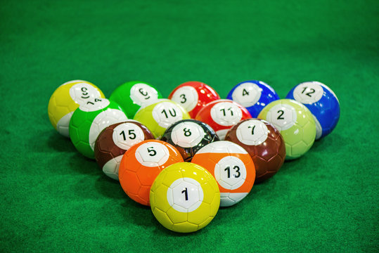 Shot of foot pool balls standing on green table. Foot Pool is the hybrid combination of pool and soccer. Big billiard balls. 
