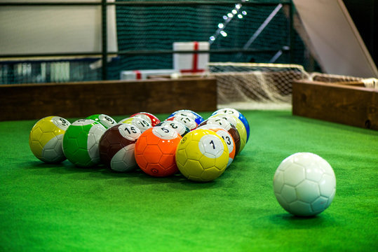 Shot of foot pool balls standing on green table. Foot Pool is the hybrid combination of pool and soccer. Big billiard balls. 
