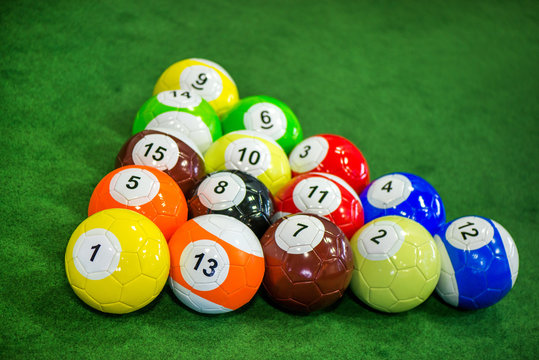 Shot of foot pool balls standing on green table. Foot Pool is the hybrid combination of pool and soccer. Big billiard balls. 
