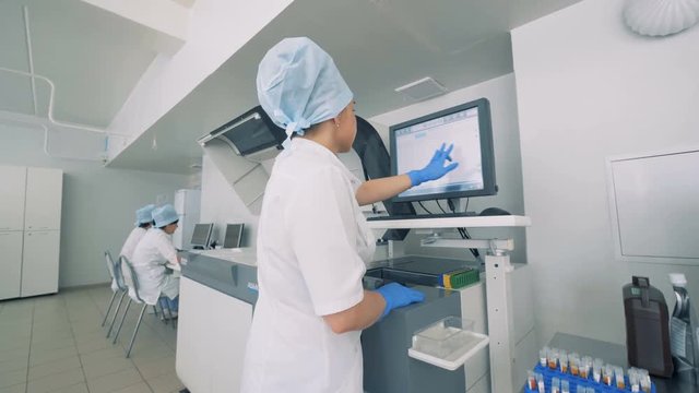 Laboratory facility with a female lab expert working with touchscreen on a Automatic Pharmaceutical Equipment.