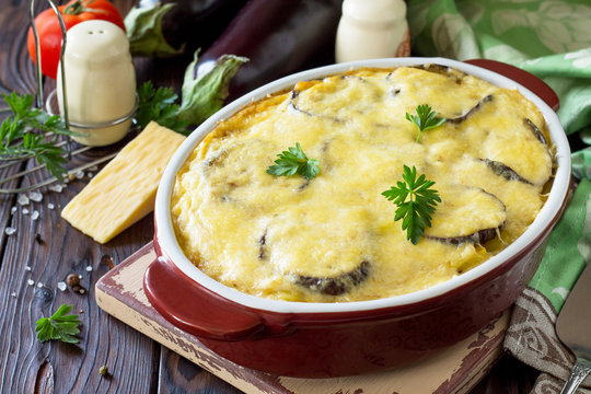 Eggplant casserole with beshamel (moussaka) - a traditional Greek dish on the kitchen wooden background.