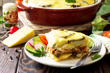 Eggplant casserole with beshamel (moussaka) - a traditional Greek dish on the kitchen wooden background. Copy space.