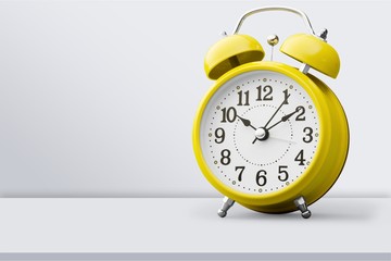 Yellow retro alarm clock on wooden table and wall background